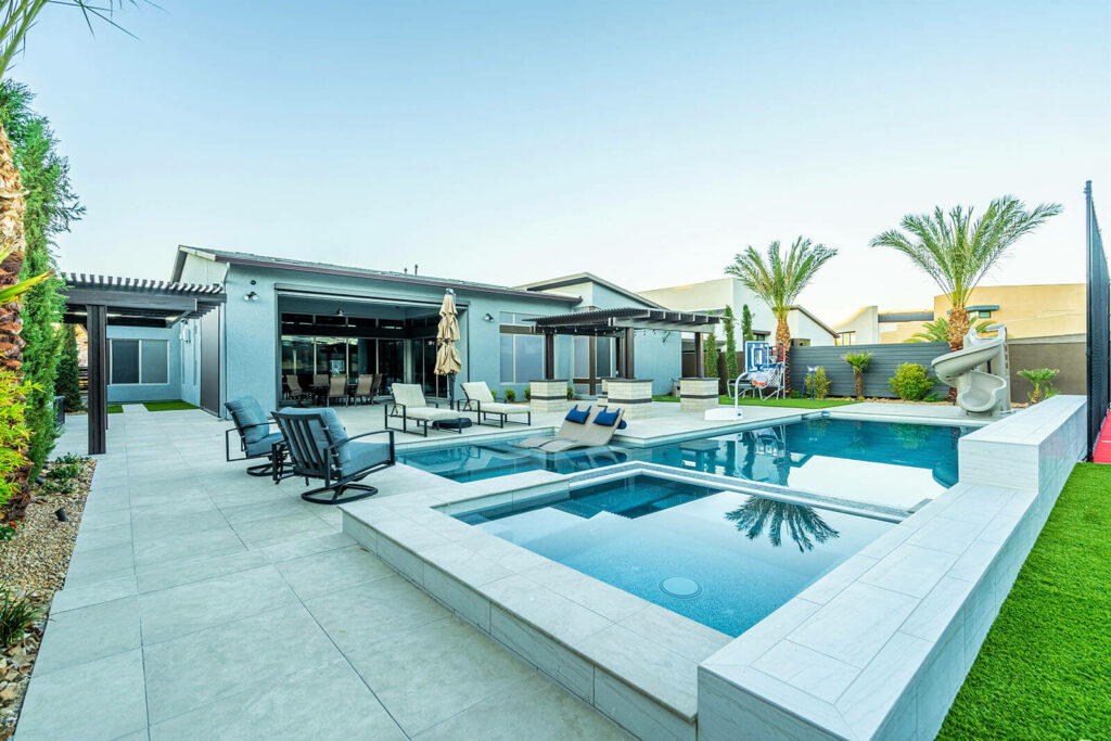 A backyard featuring a swimming pool surrounded by patio furniture for outdoor living spaces and relaxation.