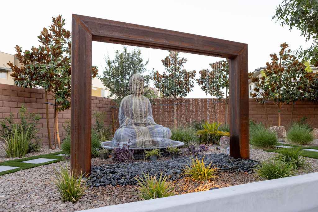 A tranquil garden scene with a Buddha statue at the center, framed by vibrant plants and blooming flowers.