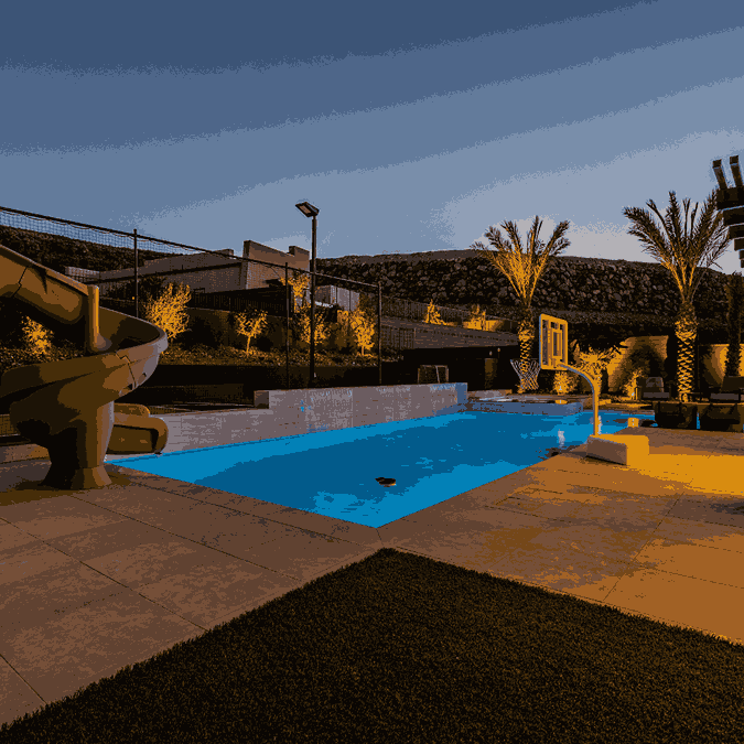 A pool featuring a slide and a water slide, illuminated by landscape lighting for a vibrant evening atmosphere.