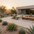 A beautifully designed sustainable landscape illustrating modern desert minimalism. In the foreground, a variety of drought-resistant plants, including succulents and cacti, are meticulously arranged on soft, natural gravel pathways. In the middle ground, desert-focused xeriscaping techniques adorn the space, featuring drip irrigation systems and strategically placed shaded seating areas made of reclaimed wood. The background showcases a minimalist modern home with large windows to maximize natural light, surrounded by native flora that flourishes under the warm sun. The scene is bathed in soft golden light, creating a calm and serene atmosphere, with the sun setting slowly in the distance. The angle of the shot is slightly elevated, providing a comprehensive view of the harmonious design and sustainable practices at play.